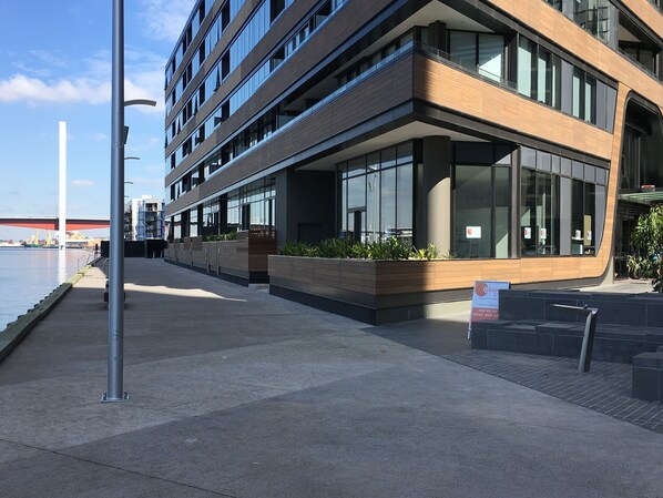 Un edificio moderno con fachada de vidrio, vista al agua y un cartel que indica un restaurante.