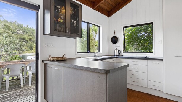 Una cocina moderna con una isla grande, armarios blancos y vistas al exterior.