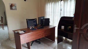 Ein Holztisch mit einem Computer, einer Tastatur und verschiedenen Büroutensilien. Ein Stuhl steht dahinter.