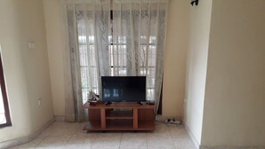Ein Wohnzimmer mit Fernseher auf einem Holzständer, einem Schiffmodell und einer Mehrfachsteckdose auf dem Boden.
