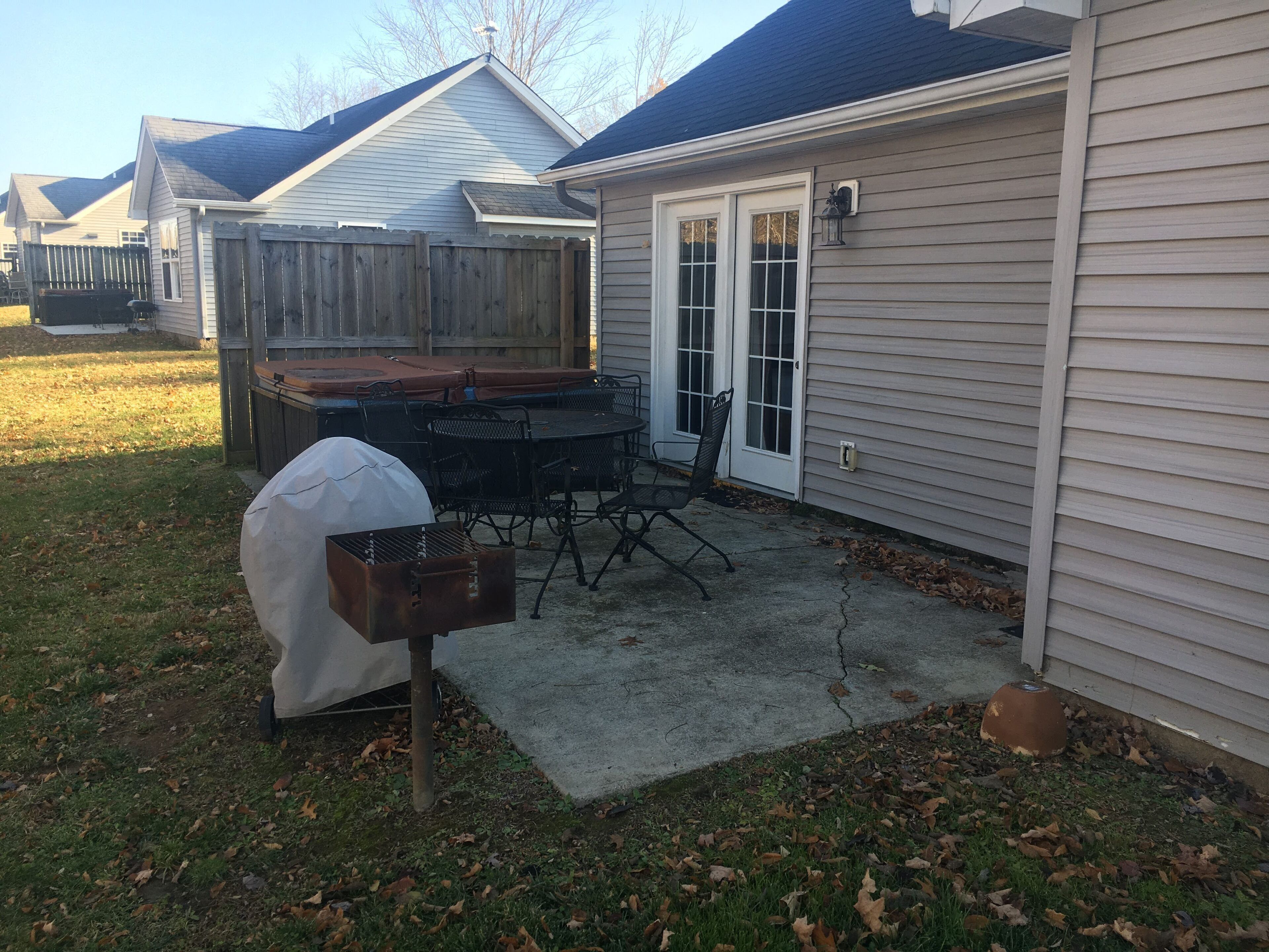 Un patio trasero con una parrilla, muebles de exterior y una mesa cubierta para la parrilla.