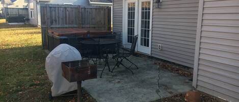 Un patio trasero con una parrilla, muebles de exterior y una mesa cubierta para la parrilla.