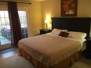 A neatly made bed with a headboard, a bedside lamp, and a painting on the wall. - GET AWAY FROM IT ALL - Cottage 28 Taylorsville Lake (Taylorsville)