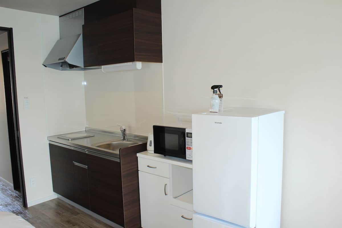 A compact kitchen with a microwave, refrigerator, and a sink.