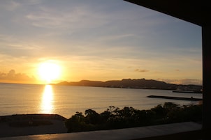 A sunset over a calm sea with distant landforms and a clear sky.