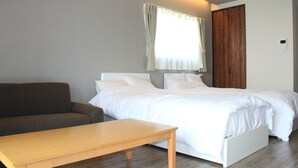 A bedroom with a bed, a wooden table, and a sofa.
