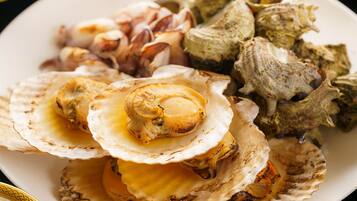Un plato de vieiras cocinadas y diversos tipos de mariscos.