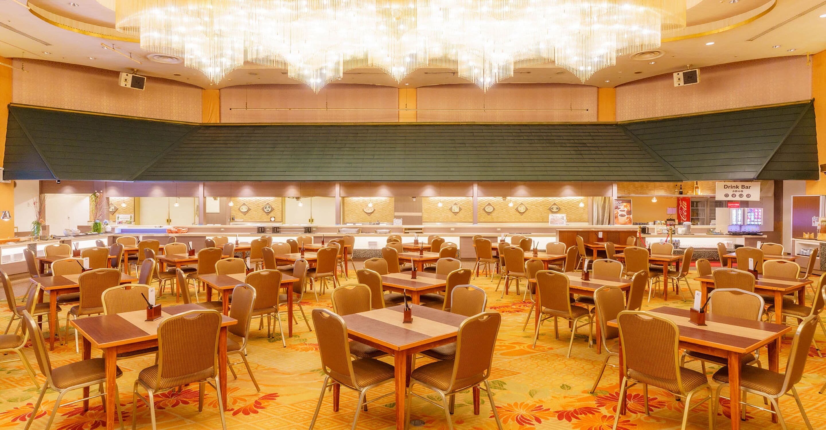 Un grand espace dédié à la salle à manger, avec de nombreuses tables et chaises, un bar central et un lustre.