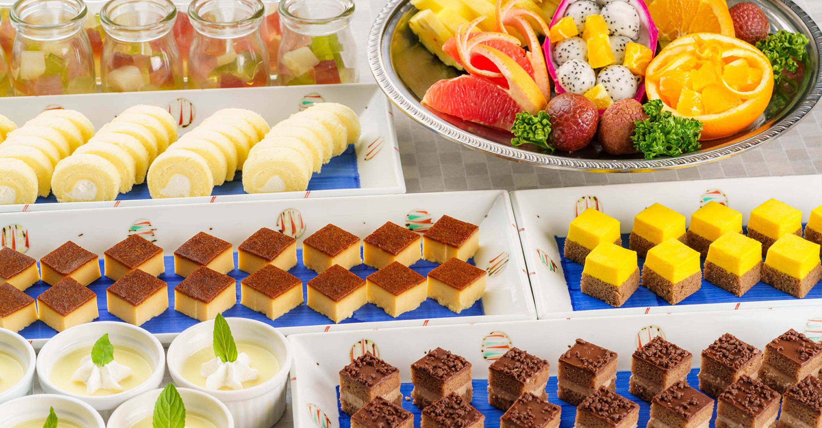 A variety of desserts including cakes, brownies, and fruit arrangements.