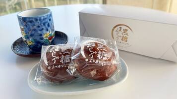 A table with a blue ceramic cup, a white box with Japanese text, and two packaged items on a plate.