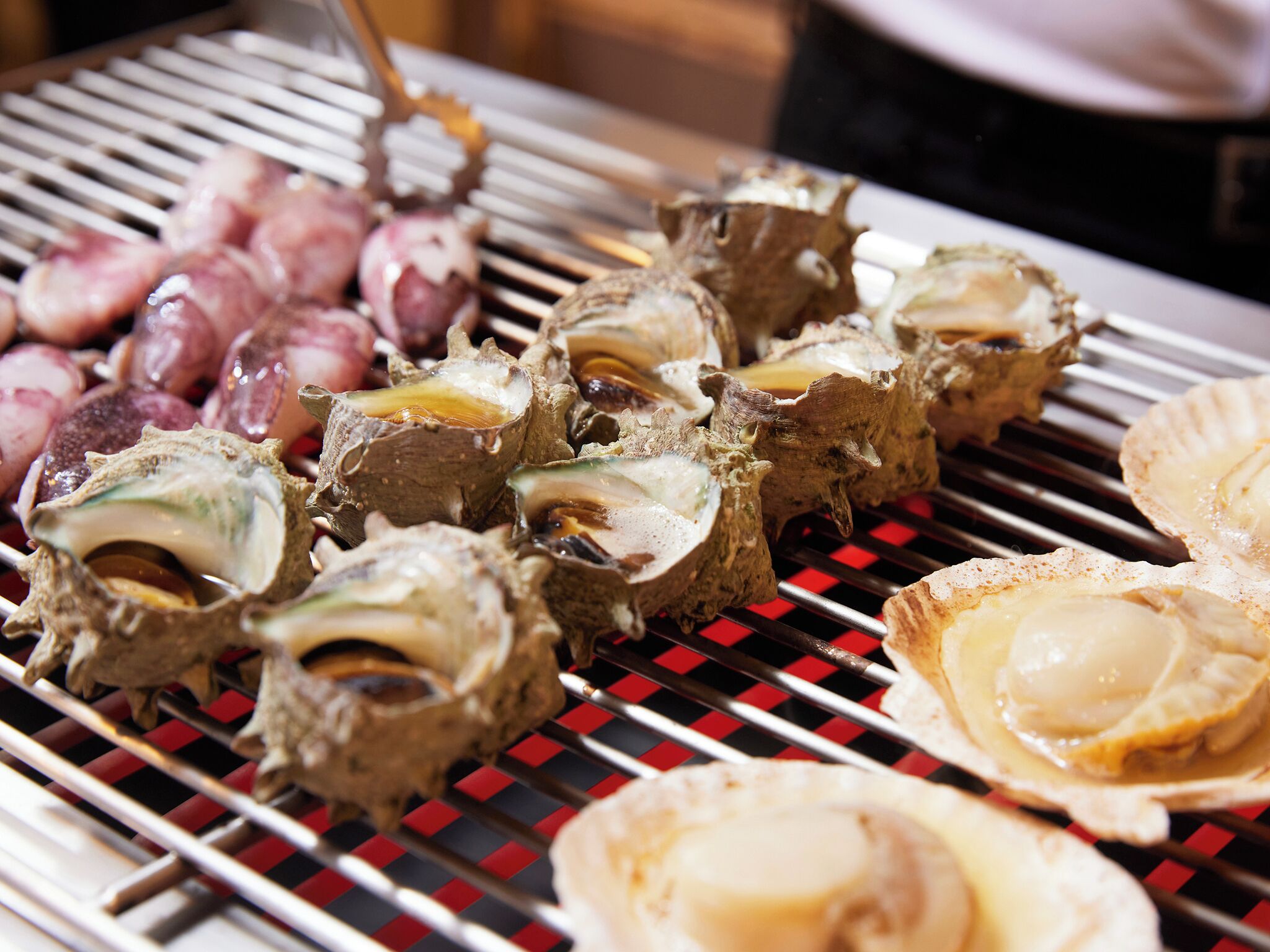 A grill with various seafood items, including oysters and possibly other shellfish.