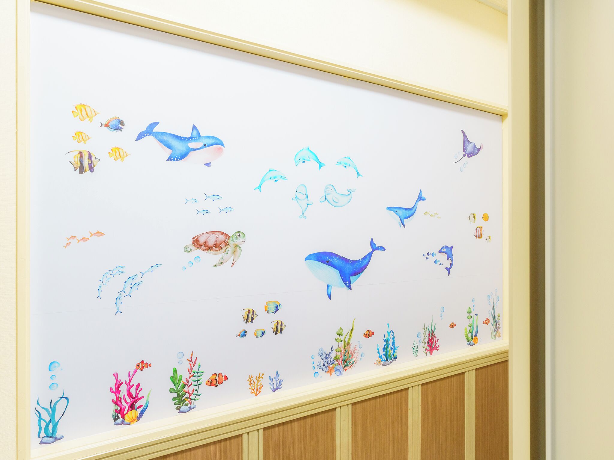 Un mur orné d’une fresque sur le thème de la mer, représentant différentes créatures marines et des coraux.