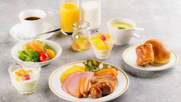 Un desayuno con diferentes platillos, como huevos, jamón y tostadas, además de bebidas como jugo de naranja y café.