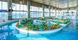 A large indoor swimming pool with multiple lanes, surrounded by flower beds and decorative elements. -  Mikazuki Sea-Park Hotel Katsuura (Katsuura)