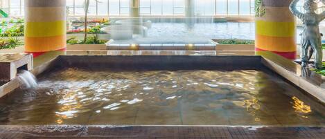 A hot spring area with a central fountain, tiled walls, and decorative columns.