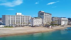 Um hotel à beira-mar com vários andares, uma praia de areia e águas azul-claras.