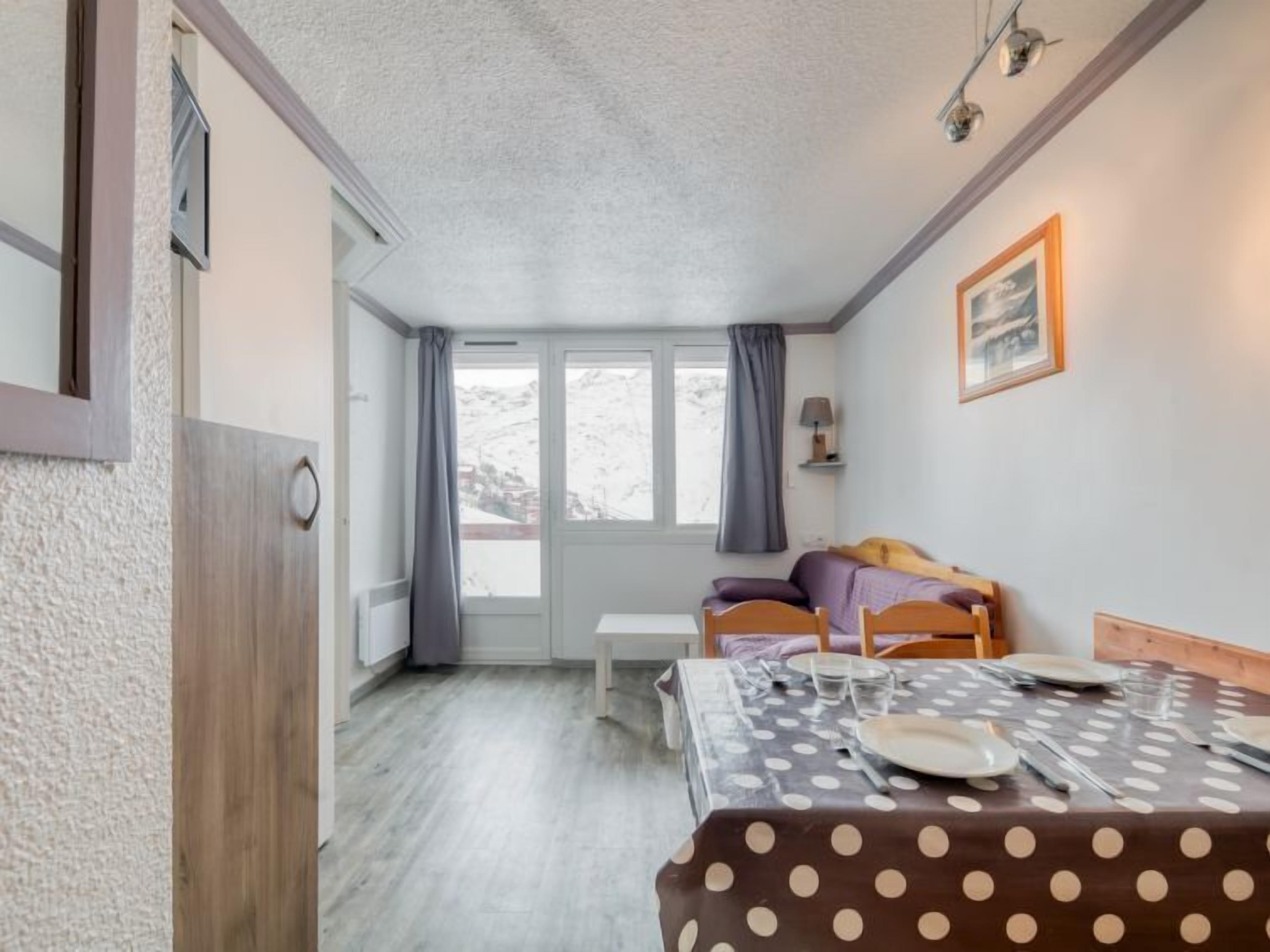 A cozy room with a bed, a small table, and a window with curtains.