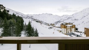 Eine verschneite Berglandschaft mit Skipiste, Gebäuden und einer Seilbahn.