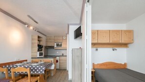 Ein gemütlicher Raum mit Esstisch, Stühlen, einem Bett und einer Küchenzeile.