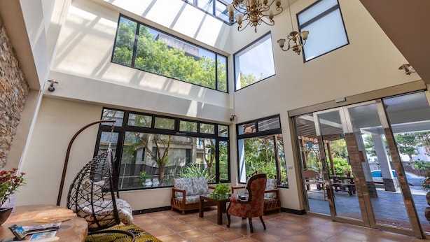 A spacious room with large windows, a hanging chair, and a dining area with chairs and a table. - Jimei Rustic Homestay (Ji'an)