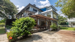 A modern two-story house with a covered patio, a balcony, and a garden area. - Jimei Rustic Homestay (Ji'an)