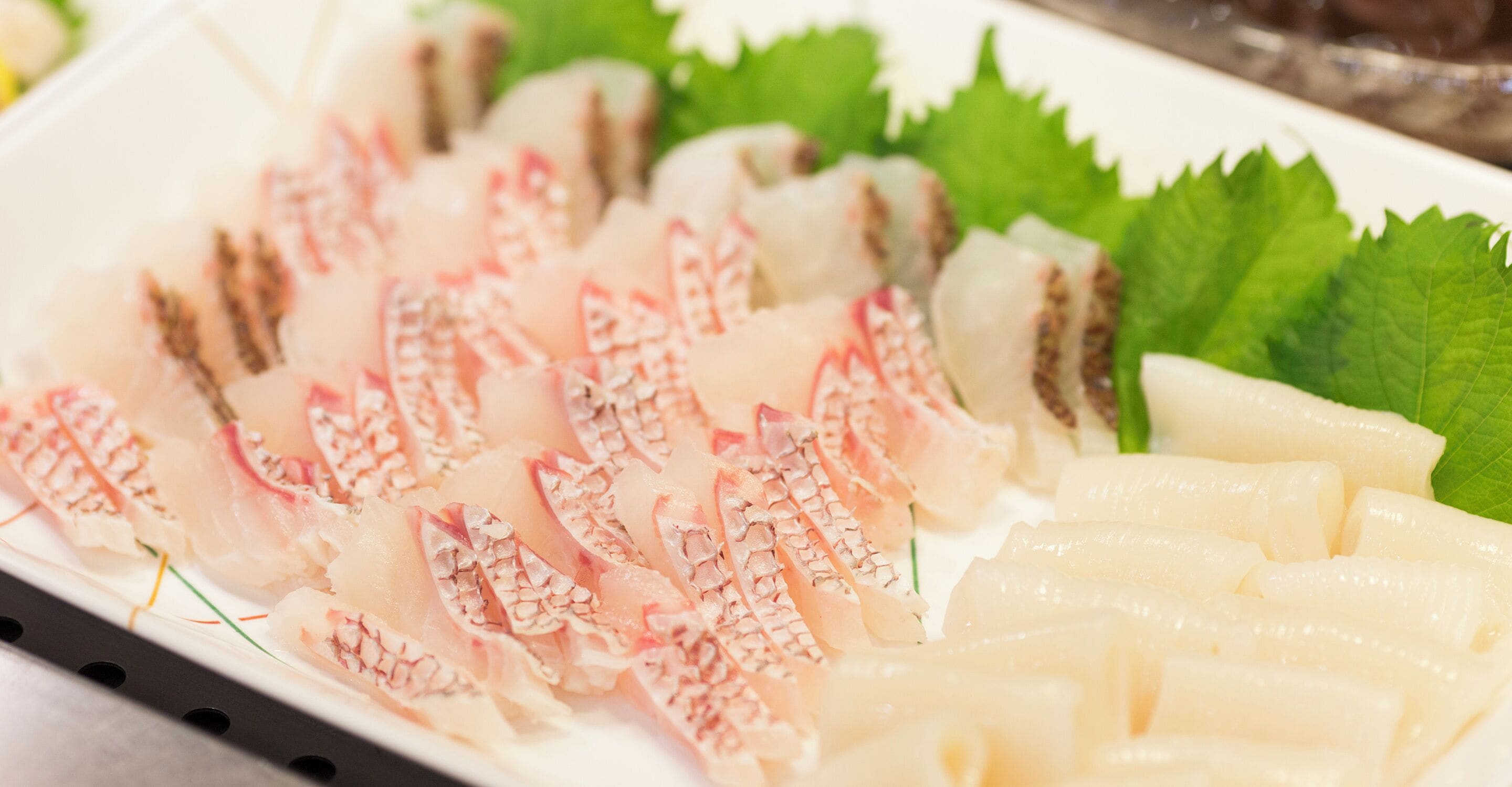 Une assiette de sashimi, composée de différentes sortes de poisson coupé en tranches et agrémentée de garnitures.
