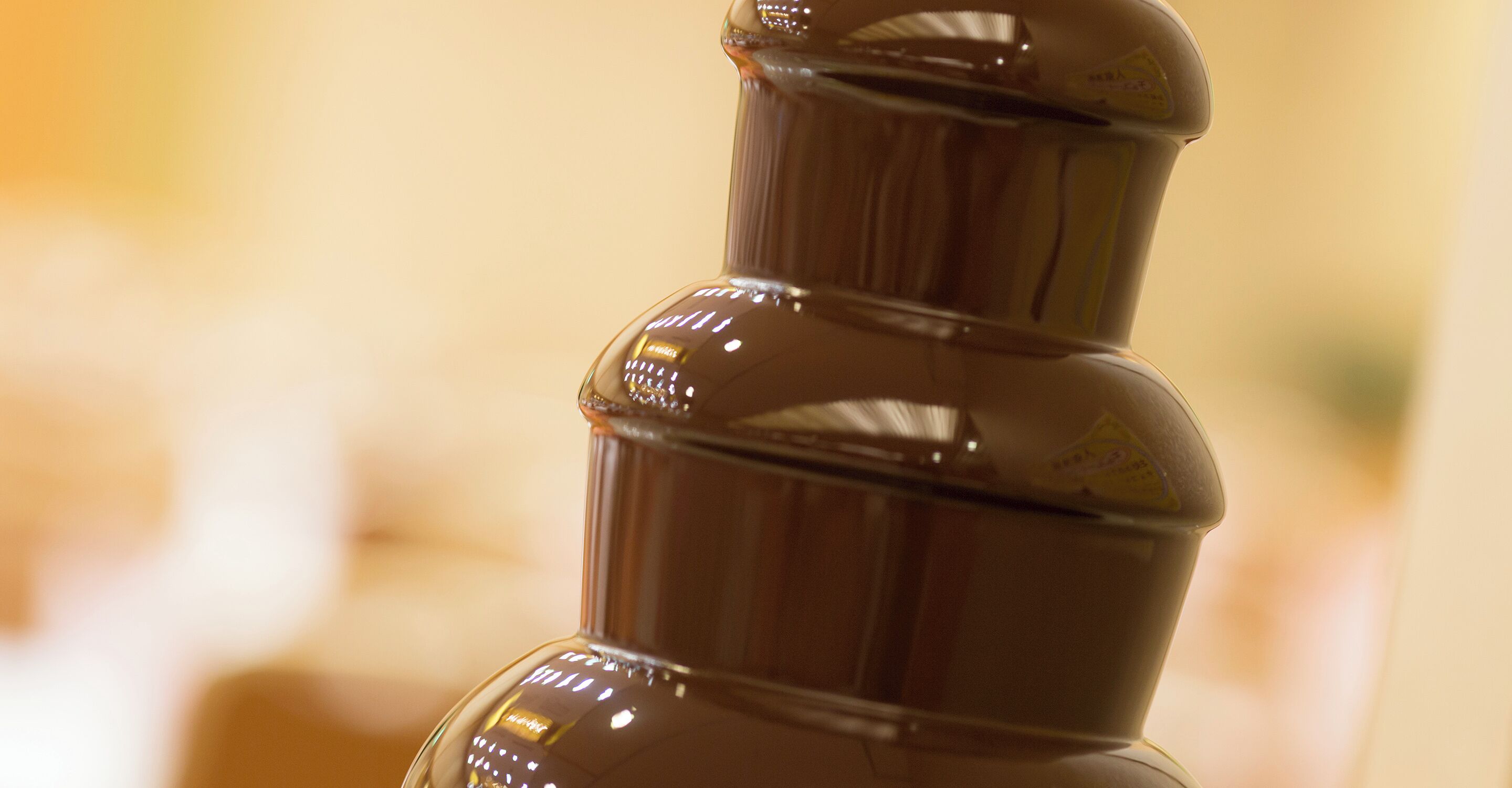 A close-up of a chocolate fountain with a glossy finish and reflective surface.