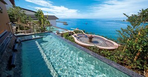 Uma piscina com vista para o mar, uma banheira de hidromassagem e um deck de madeira com grades.