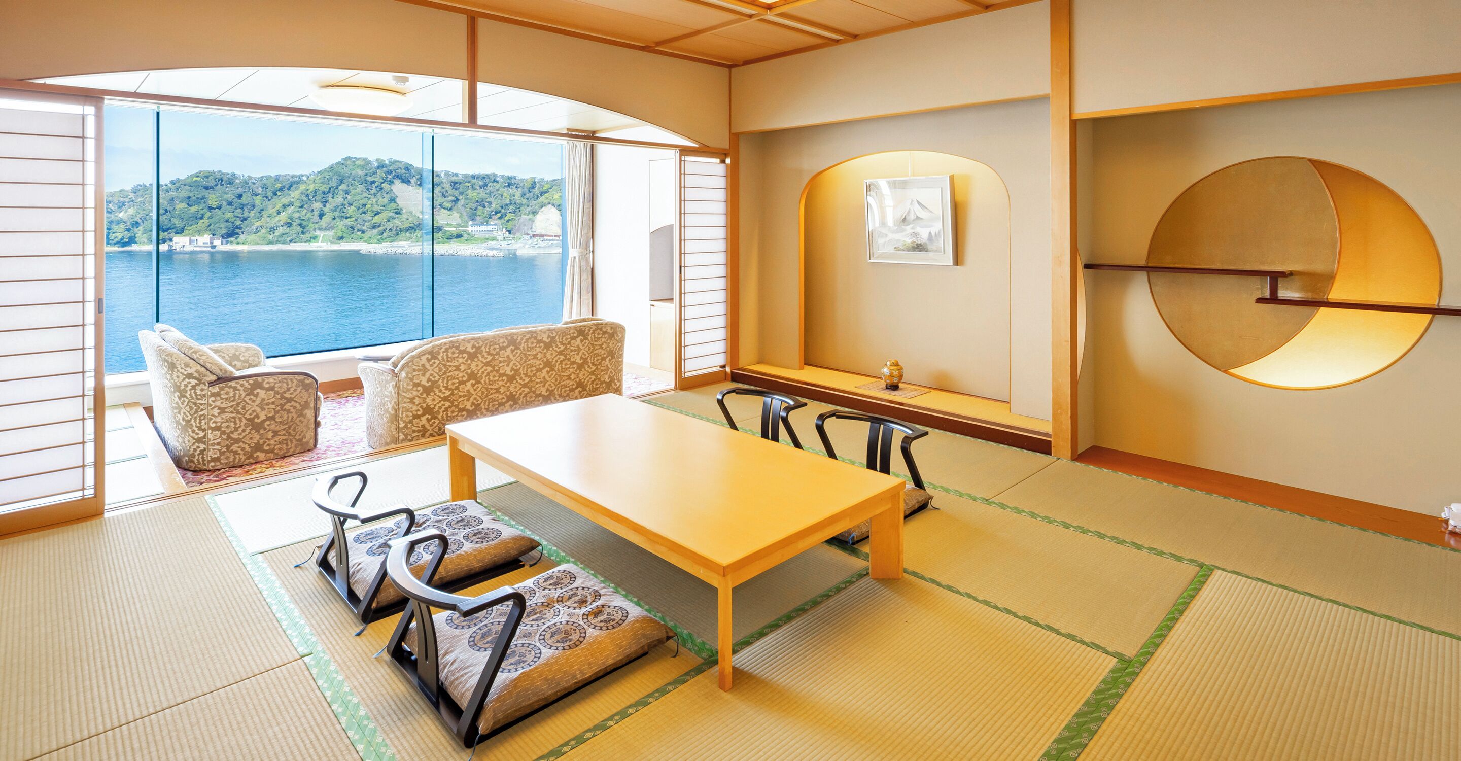 A traditional Japanese room with tatami flooring, a low table, and chairs.