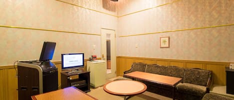 A small, private room with a desk, a computer, a sofa, and a small table.