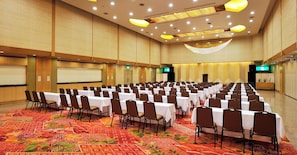 A conference room with rows of tables and chairs, a projector screen, and a stage area. - Mikazuki Sea-Park Hotel Awa Kamogawa (Kamogawa)