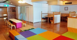 Un espace de jeux pour enfants avec un sol coloré, une petite table et des chaises.
