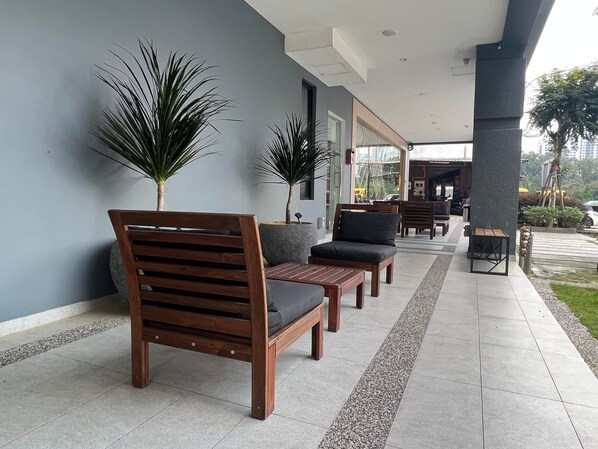 Un área de estar al aire libre con techo, mobiliario de madera y plantas en macetas.