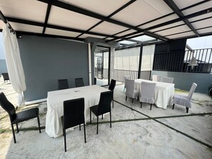An outdoor patio with a table and chairs, a covered area, and a view of the surrounding area. - Miyabi Hotel (Masai)