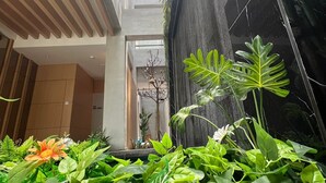 A modern building with a central atrium, surrounded by lush greenery and plants. - Miyabi Hotel (Masai)
