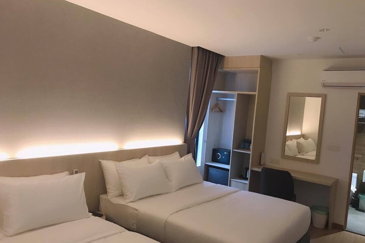 A hotel room with two beds, a walk-in closet, a desk, and a mirror.