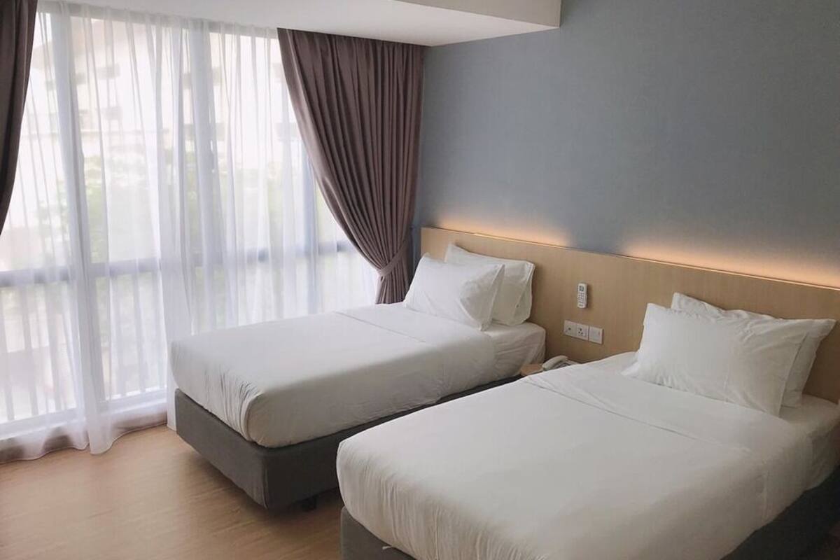 Two single beds with white linens in a hotel room.