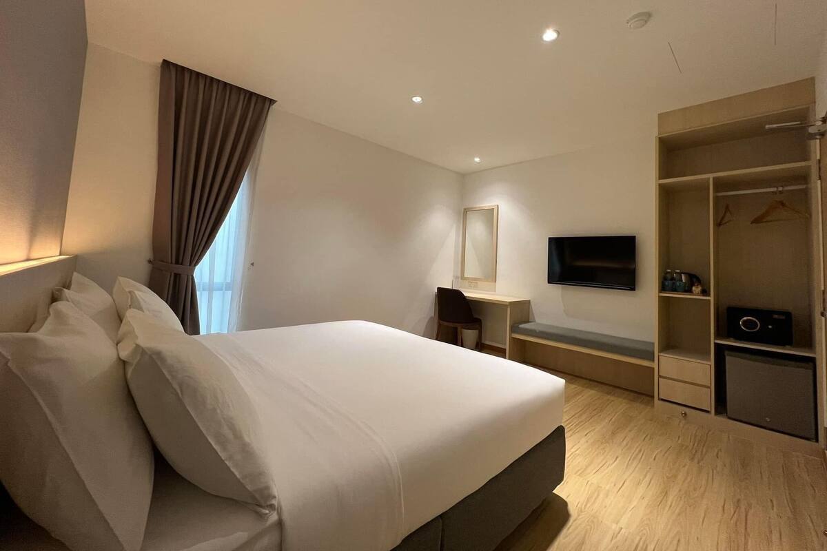 A hotel room with a bed, a desk, a chair, a TV, and a walk-in closet.