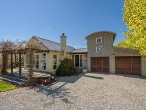 A two-story house with a gravel driveway, a garage, and a covered porch area.