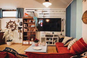 A living room with a TV, bookshelf, and a red sofa.