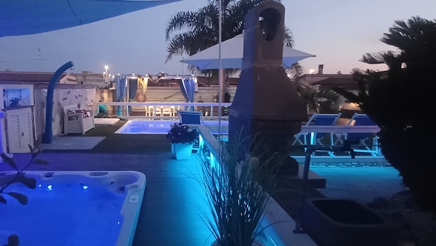 Un área de piscina con un jacuzzi, sillas de descanso y sombrillas.