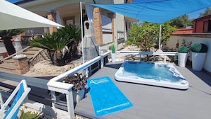 Un jacuzzi, mobiliario exterior y un cartel azul con una dirección web.
