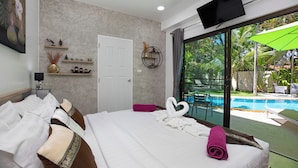 Ein Hotelzimmer mit Bett, Fernseher, einer Tür und Blick auf einen Swimmingpool.