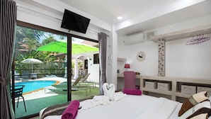 Ein Hotelzimmer mit Bett, Schreibtisch, Stuhl, Fernseher und Blick auf einen Pool.
