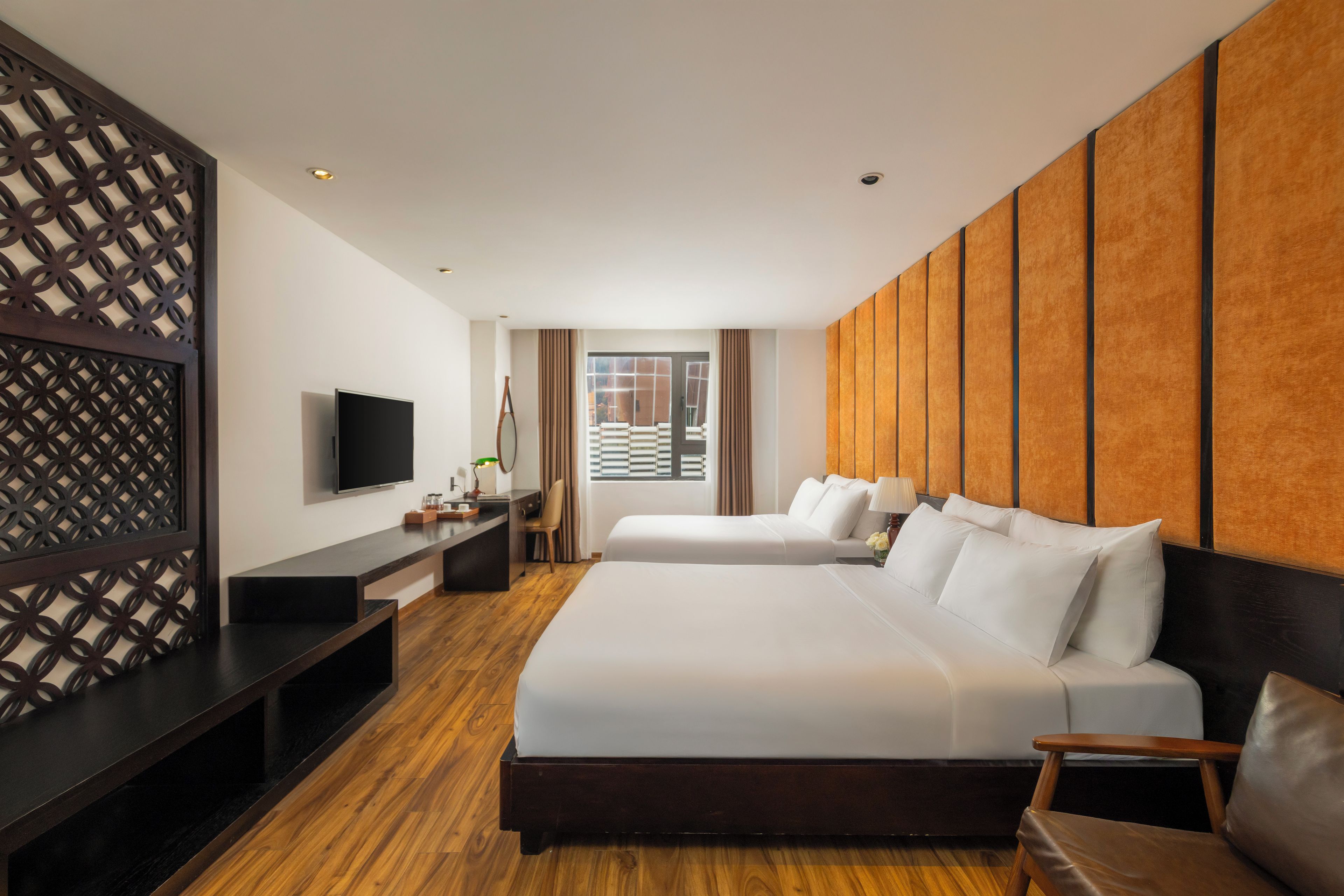 A hotel room with a large bed, a desk, a television, and a view of the outside.