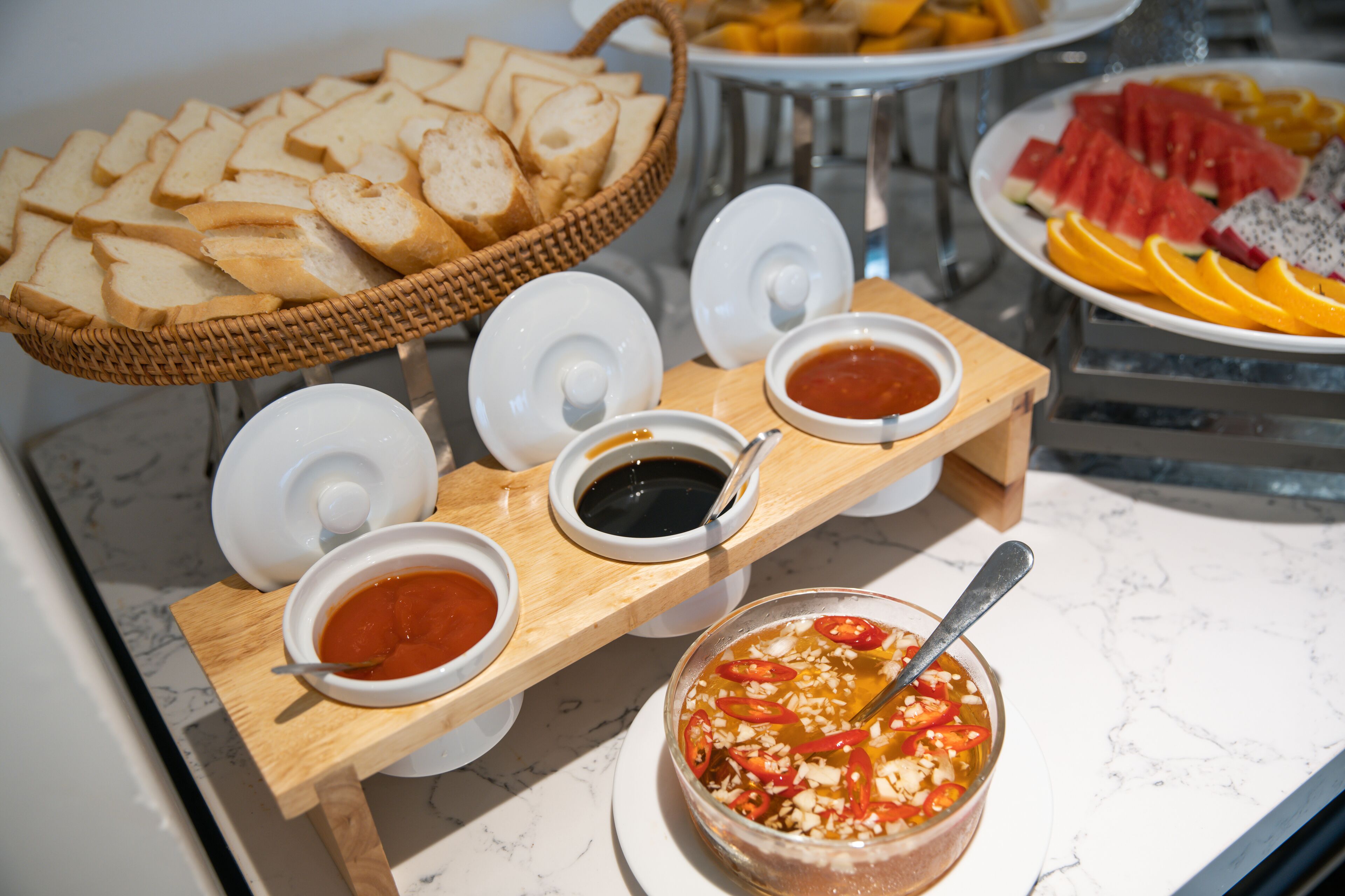 Ein Buffet mit Brot, Obst und verschiedenen Soßen.