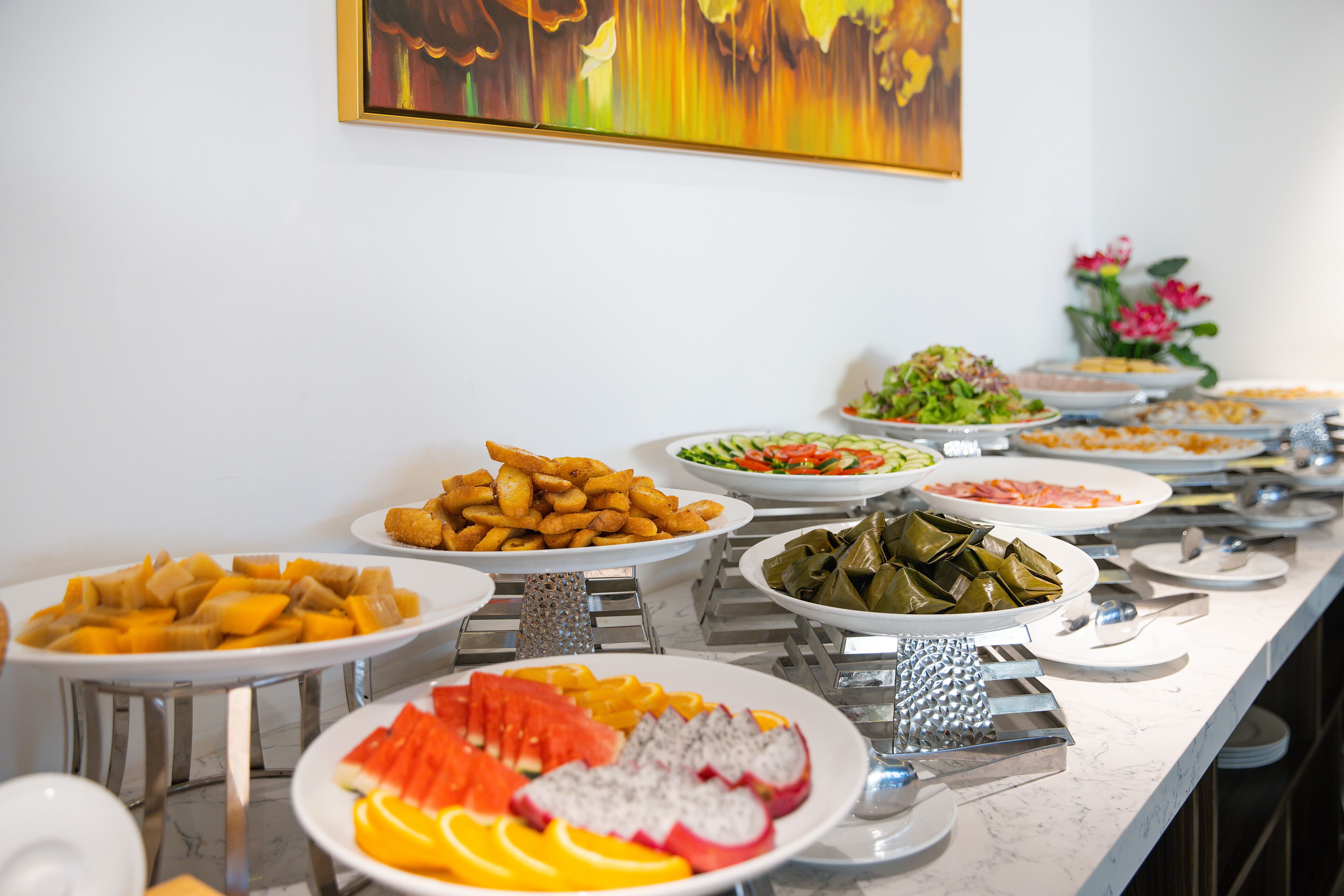 Un bufé con diversos platos, entre ellos frutas, verduras y alimentos preparados.