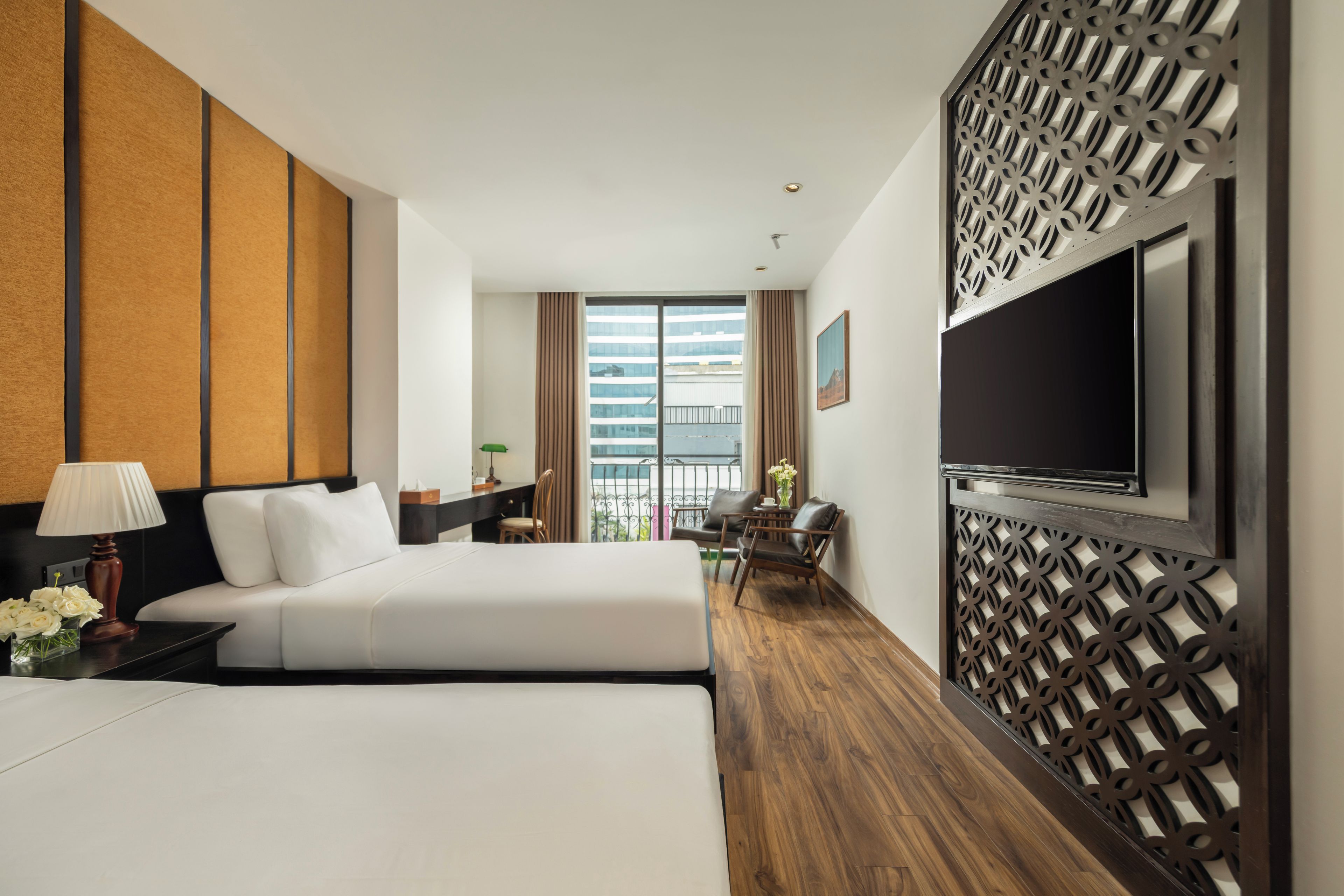 A hotel room with two beds, a TV, a desk, a chair, and a view of a building.