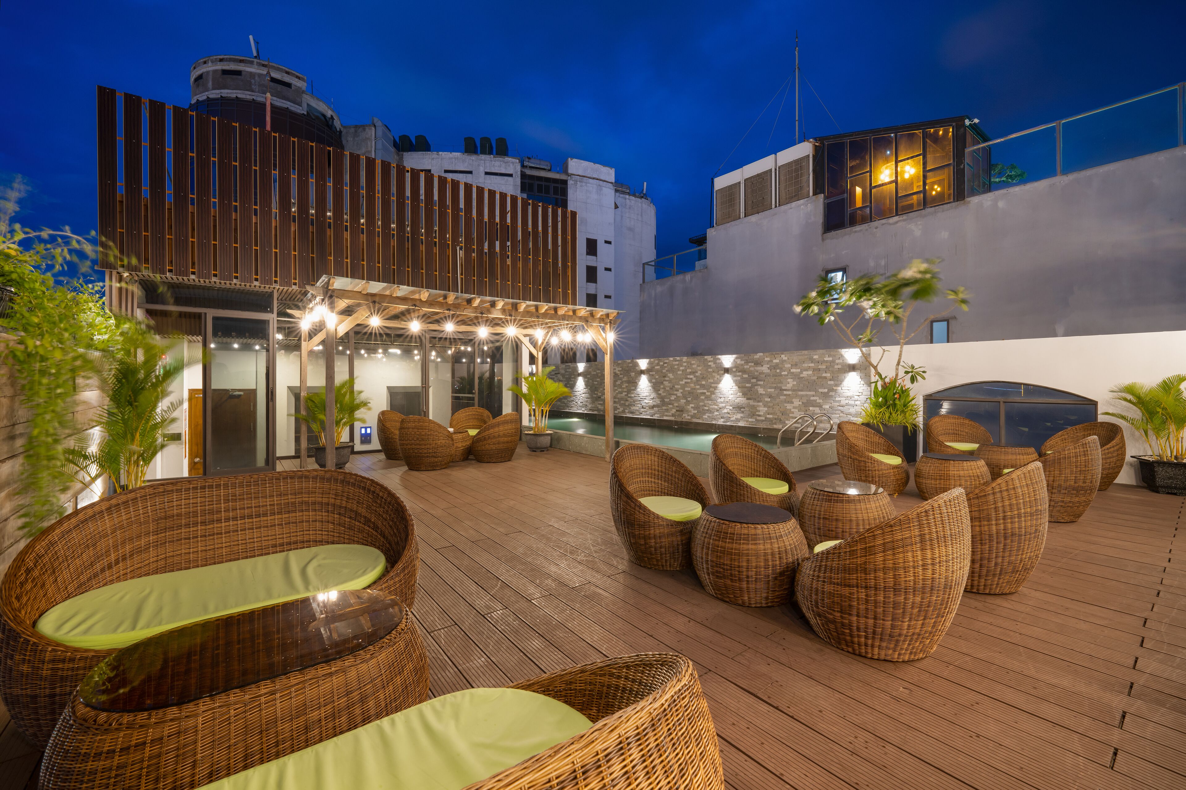 A rooftop terrace with wicker furniture and a pool.