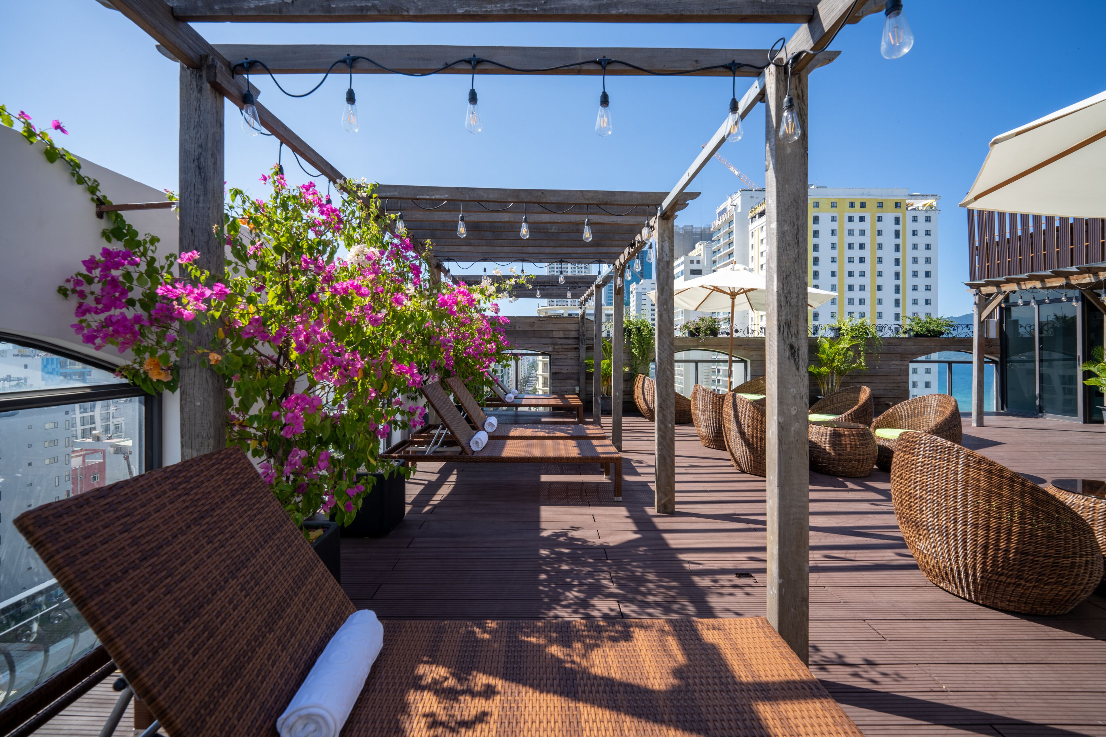 Eine Dachterrasse mit Holzboden, Korbmöbeln und Blumentöpfen.
